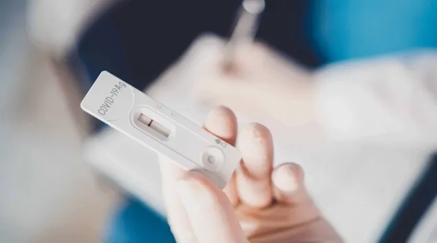 A COVID-19 test strip in a hand