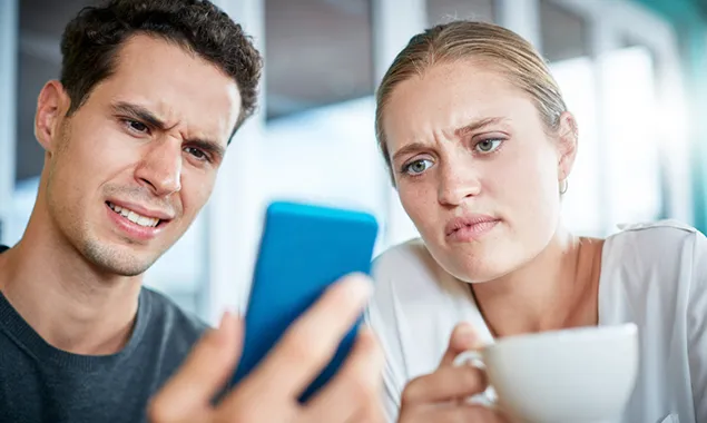 Two people puzzle over a phone display