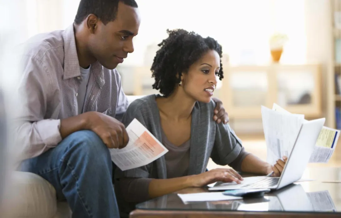 A couple with bills and a laptop