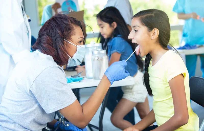 Doctor using a tongue depressor on young patient Doctor using a tongue depressor on young patient