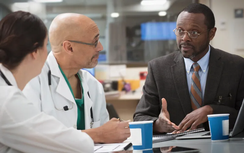 Doctors meet with man in suit Doctors meet with man in suit