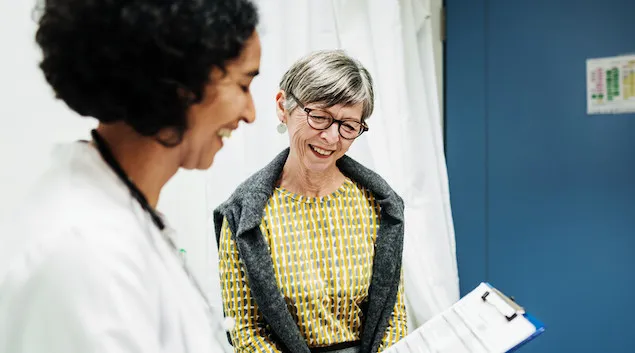 Senior patient meeting with their doctor and looking at forms on a clipboard