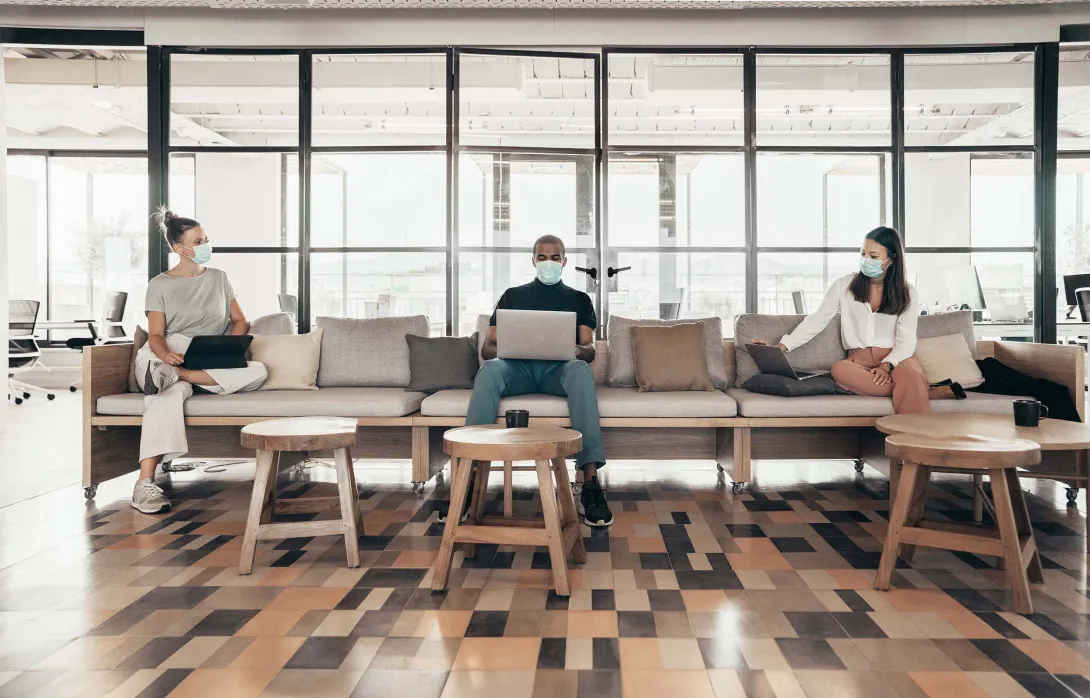 Open office with workers in masks on a couch Open office with workers in masks on a couch