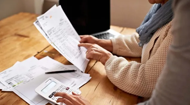 Two people with paperwork and calculator