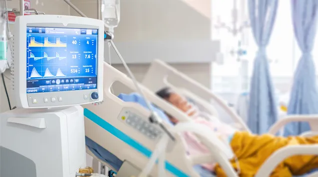 A screen with readings next to an occupied hospital bed