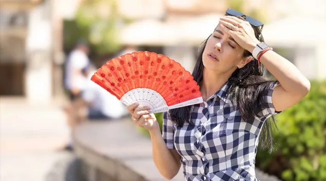 Woman fanning herself in the heat Woman fanning herself in the heat