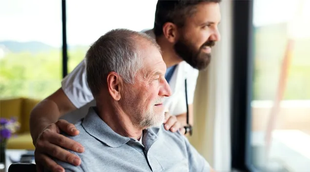 Senior and younger caregiver looking out a window
