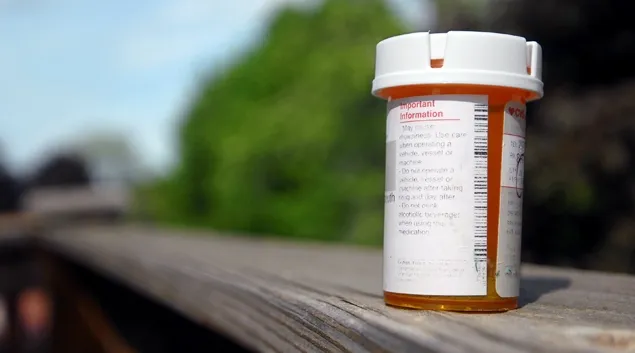 Pill bottle on outdoor deck railing Pill bottle on outdoor deck railing
