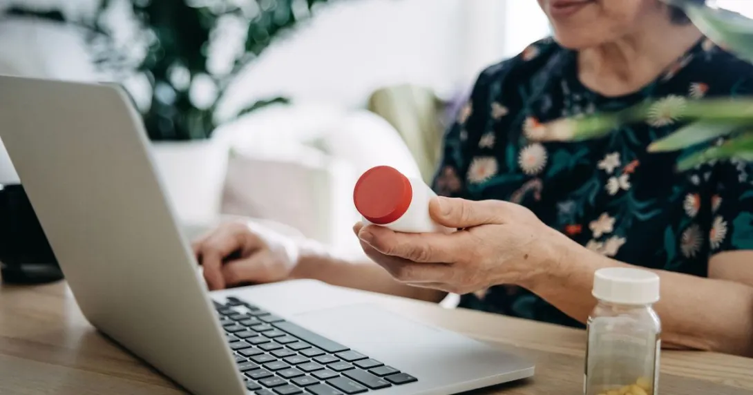 Person holding perscription bottle and using laptop