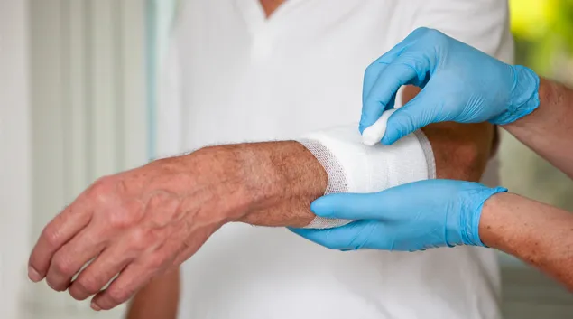 Gloved hands apply wound dressing