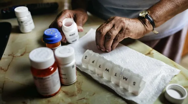 Hands sorting through pillbox