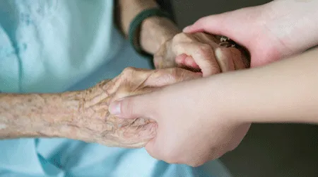 close up on nurse holding elderly hands