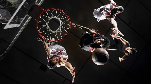 Basketball players playing on a dark court