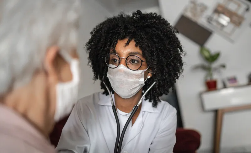 Health professional in mask speaks with a person