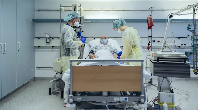 Healthcare workers in PPE care for COVID-19 patient in a hospital