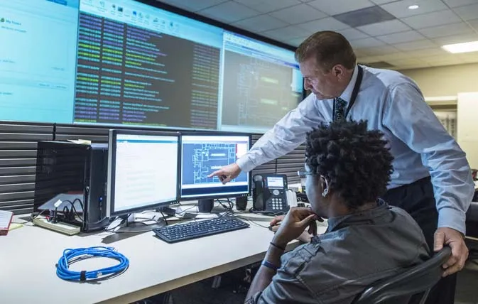 Two people discuss info on screens