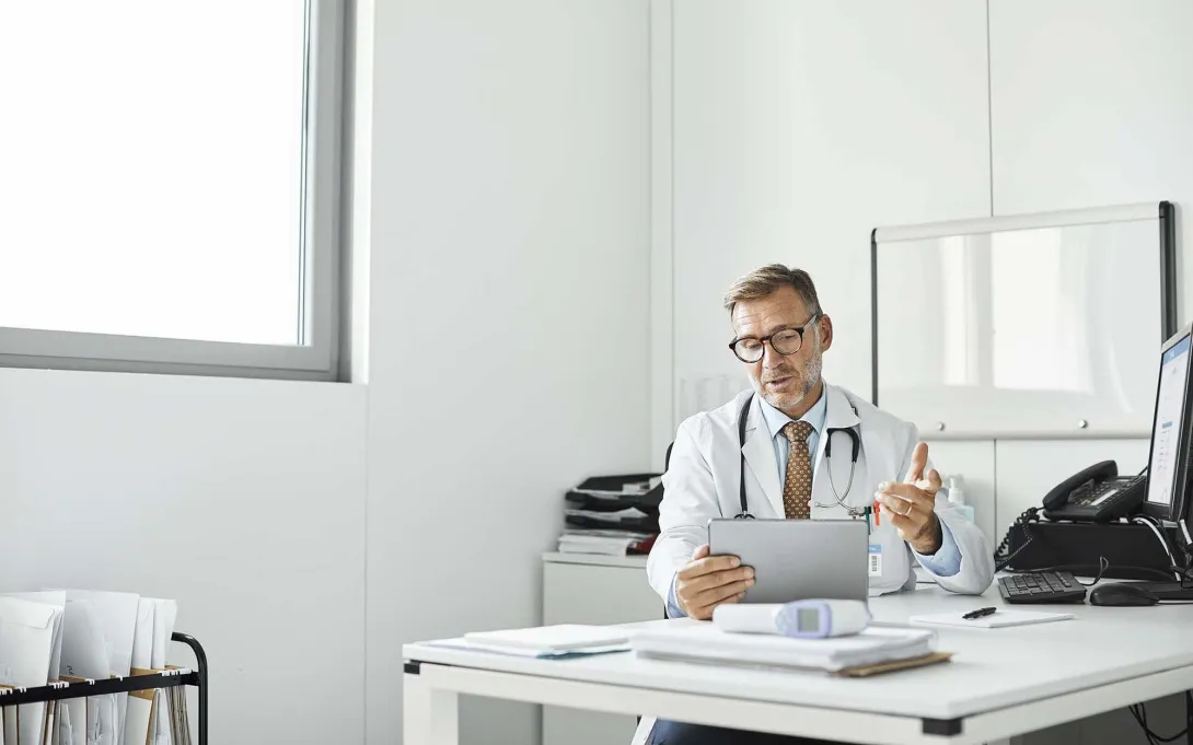 Healthcare professional at desk and holding a tablet