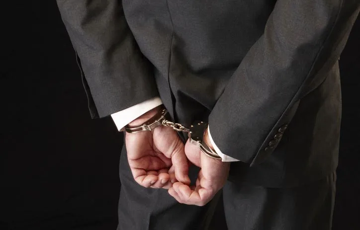 Person in suit handcuffed. Photo: Hirkophoto/Getty Images