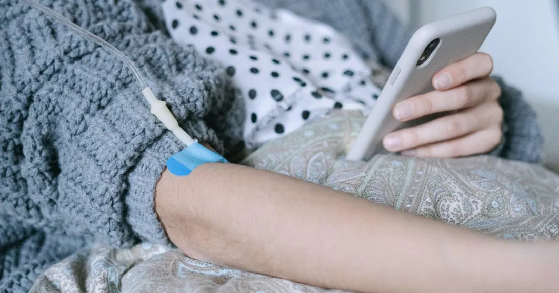 IV in arm of patient holding smartphone