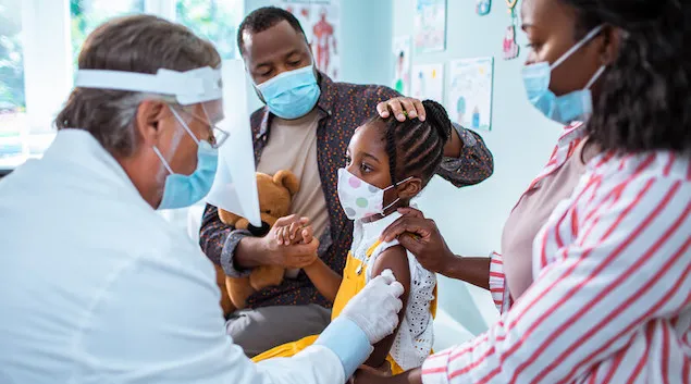 Young child getting a vaccine with their parents