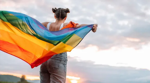 Person holding LGBTQ+ rainbow flag