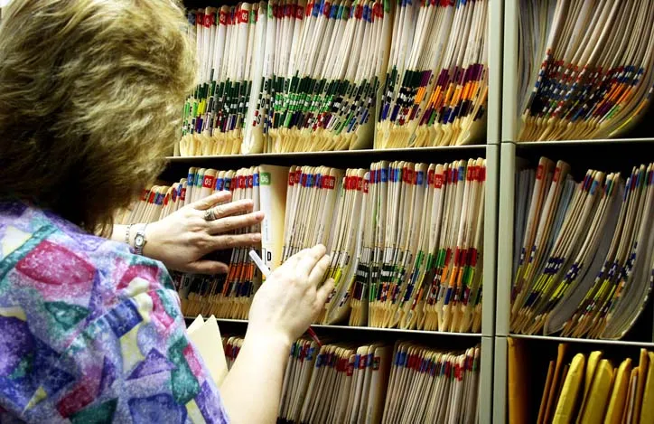 A person in front of a shelf of medical folders