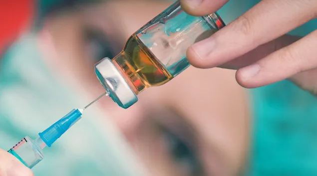 Close-up of a healthcare worker extracting a vaccine from a vile