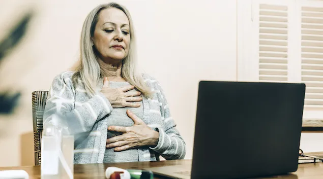 Woman doing breathing exercises in front of a laptop