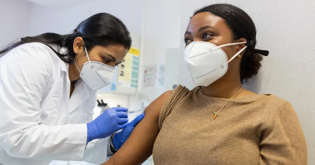 Healthcare worker in mask vacinating patient in mask