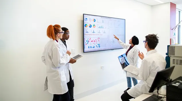 Medical professionals with a large screen of graphs and pie charts