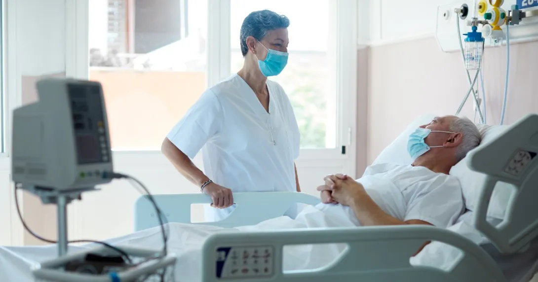 Doctor in mask talking to patient in hospital bed with mask