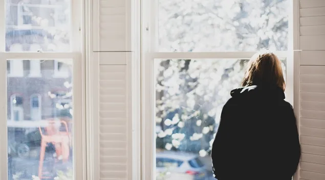 Person looking forlornly out a window