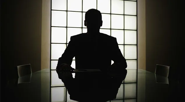 Silhouette of someone looking out a board room window