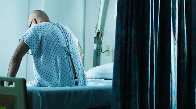Person sits at side of hospital bed