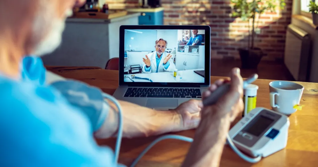 Patient using blood pressure cuff while talking to doctor on laptop screen